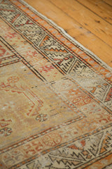 Angled detail of a vintage distressed Oushak runner with faded pile, tangerine, and charcoal border.