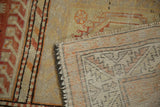 Distressed Oushak rug showing hand-knotted foundation, fringed end, and original side selvage.