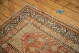 Distressed Oushak runner corner showcasing geometric borders in tangerine orange and antique ivory.