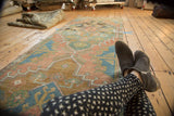 Distressed Oushak runner's worn knot heads, soft terra cotta, and pale teal geometric patterns.