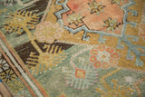 Distressed Oushak rug detail: faded geometric florals in dusty terra cotta and pale teal.