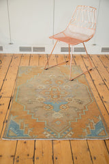 Distressed Oushak rug fragment corner with beige and pale blue floral vinery.