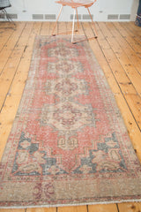 Textured pile of distressed Oushak runner with repeating medallions in pale red, blush, and silver.
