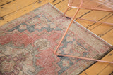 Distressed pile texture of a vintage Oushak runner featuring soft cinnabar and charcoal gray geometric patterns.