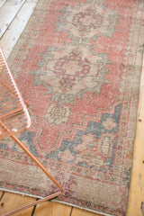 Distressed Oushak runner's hand-knotted texture with faded cinnabar red and charcoal pattern.