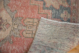 Distressed Oushak rug pile with muted cinnabar and charcoal, revealing hand-knotted reverse.