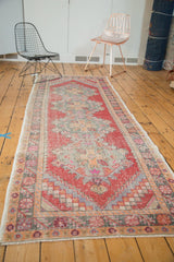 Distressed vintage Oushak runner's side border and warm red, green, and tangerine palette.