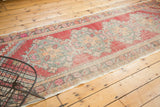 Worn texture and side selvage of distressed Oushak runner in cherry red, seafoam green.