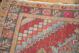 Distressed Oushak rug detail: stepped check spandrel in cherry red, tangerine, and charcoal.