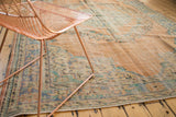 Distressed vintage Oushak rug pile with faded peach, mint, and pale blue florals.