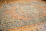 Edge of vintage distressed Oushak carpet, featuring pale royal blue floral border and visible textured pile.