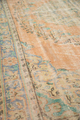 Textural close-up of distressed vintage Oushak rug pile with softened peach and mint tones.