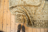 Vintage Turkish Oushak carpet corner featuring ivory, pale bronze floral motifs, and a dark chocolate border.
