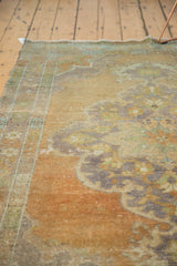 Textured distressed Oushak rug surface with faded peach, seafoam, and mauve patterns.