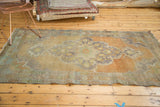 Vintage Distressed Oushak rug corner with worn pile, faded peach field, and seafoam green border.