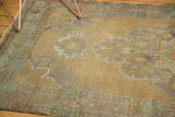 Distressed vintage Oushak rug corner highlighting worn texture and faded peach, green, ivory.