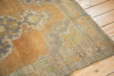 Faded peach, muted green, and mauve curvilinear spandrel on a distressed Oushak rug corner.