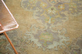 Distressed vintage Oushak rug pile revealing faded peach, green, and mauve floral motifs.
