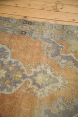 Close view of the worn hand-knotted texture and muted rococo motifs of the distressed Oushak rug.