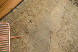 Vintage Oushak carpet: ivory field with subtle bronze pattern, dark selvage, and light staining.