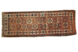 Antique Moghan Kazak runner featuring repeating gul motifs on an oxidized copper green field.