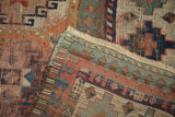Folded corner of antique Moghan Kazak rug, revealing Laleh Abassi border, fringe, and nuanced pile.