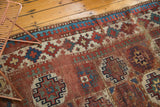 Antique Moghan Kazak runner features repeating gul motifs and Laleh Abassi pawn border, time-softened red, blue, ivory.