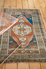 Vintage Oushak rug with abrashed terra cotta field, navy spandrel, and meandering leaf border.