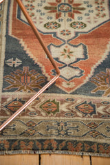 Angled view of vintage Oushak rug showing stepped spandrel and meandering floral border.
