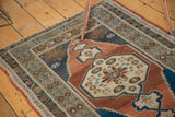 Detail of the Oushak rug's stepped terra cotta spandrel, navy field, and leaf border.