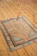 Vintage Oushak prayer rug's bottom right corner, detailing faded peach, navy, and colorful border motifs.