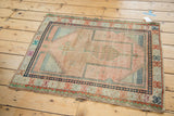 Vintage Oushak rug corner with pale blush field, intricate blue checker motif, and colorful geometric border.