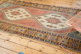 Distressed Oushak runner: ivory medallion with eggplant pinwheels, oxidized silver outlines, and geometric floral border.