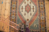 Distressed Oushak runner's central pinwheel, geometric vinery, and time-softened red, ivory, silver tones.