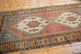 Distressed Oushak runner with an ivory corner spandrel, wine red field, and multi-color floral border.