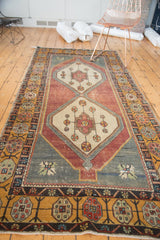 Distressed Oushak rug detail: floral border, geometric vinery, dusty eggplant field, and wear.