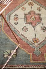 Distressed Oushak rug detail with ivory field, geometric pinwheels, and oxidized silver tones.