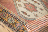 Distressed Oushak rug detail showing geometric pinwheels on ivory and a burnt orange floral border.