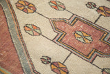 Distressed Oushak rug texture: ivory field, wine red geometry, and colorful pinwheel motifs.