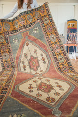 Worn ivory medallion with pinwheel and geometric vinery on a distressed Oushak runner's dusty eggplant red field.