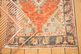 Distressed Oushak rug corner of cherry red field, platinum spandrel, charcoal border and even wear.