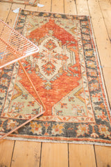 Distressed Oushak rug's faded cherry red and ivory palette with intricate floral borders.