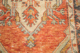 Distressed Oushak rug with faded tangerine, ivory, and grey-green stylized plant motifs.