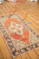 Distressed vintage Oushak runner's faded cherry red field, ivory medallion, and charcoal borders.