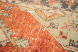 Distressed texture of vintage Oushak rug, showcasing faded cherry red and light green motifs.