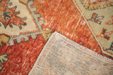 Folded corner of vintage Oushak runner, showing hand-knotted back and worn cherry red pile.