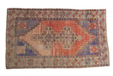 Distressed Oushak rug, faded red field, royal blue stepped medallions, ivory border.