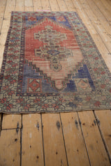 Distressed Oushak rug side showing decorative border and faded stepped field in muted tones.