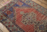 Designer-aligned distressed Oushak rug with faded brick red, royal blue, and geometric patterns.