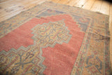 Vintage Distressed Oushak rug with serrated stepped medallion and faded cinnabar red field.